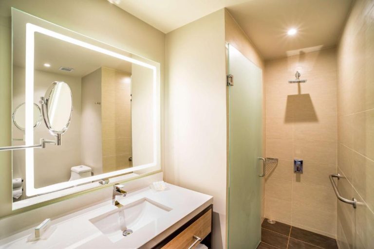 Baño moderno con ducha de lluvia y espejo iluminado en Hilton Garden Inn Bogota Airport