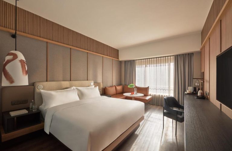 Habitación deluxe con cama king size y zona de estar en el Hotel Amara Singapore