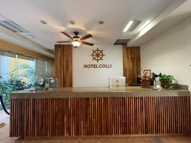 Recepción principal del Hotel Colli con mostrador de madera y logotipo náutico en la pared