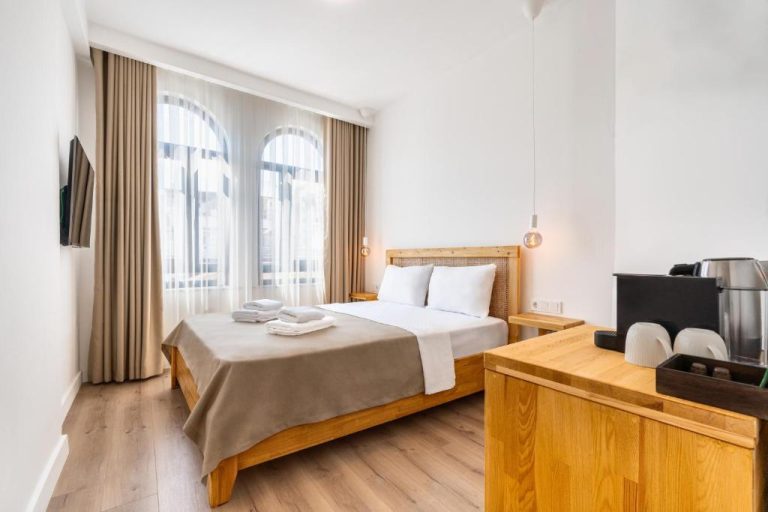 Habitación doble con cama de madera, suelo laminado y ventana amplia en el hotel Audo Local