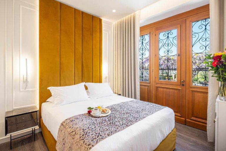 Habitación doble con cabecero tapizado en dorado y balcón en el Hotel Bella Venezia