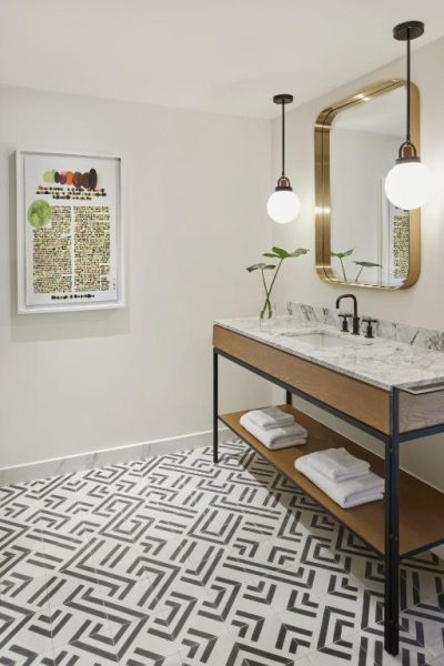 Baño moderno con encimera de mármol, espejo dorado y suelo geométrico en Kimpton Virgilio Polanco