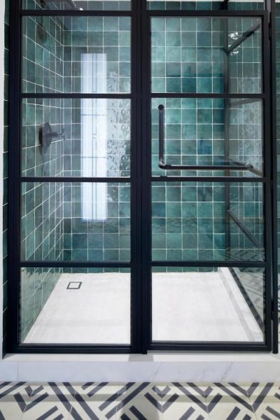 Ducha de lujo con azulejos verdes y mampara negra en el Kimpton Virgilio Polanco by IHG