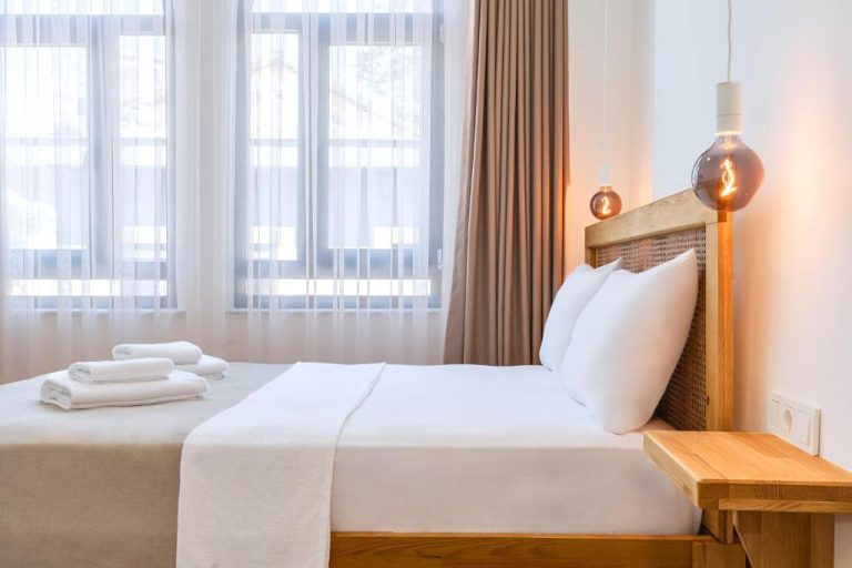 Habitación doble con cama de madera y ropa blanca en el hotel Audo Local con iluminación cálida