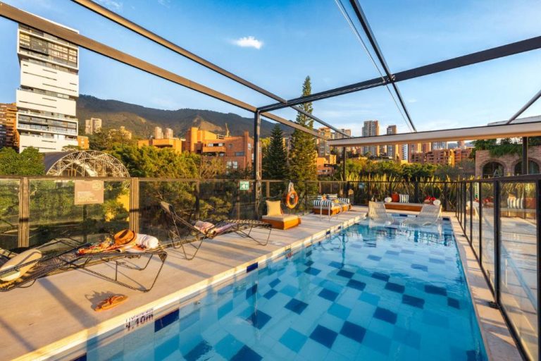 Piscina exterior con terraza y tumbonas del Loma Verde Aparthotel con vistas a la ciudad de Medellín