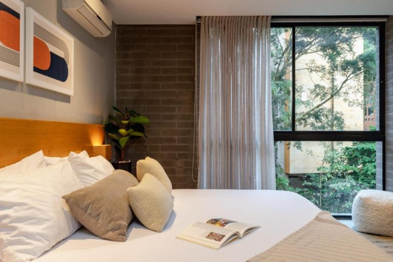 Habitación moderna con cama doble, ventanal con vistas a jardín y decoración minimalista en Loma Verde Aparthotel