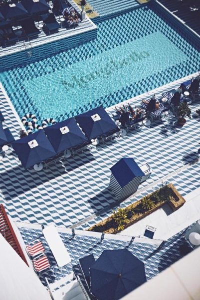 Vista aérea de la piscina exterior con tumbonas y sombrillas azules del Hotel Mongibello Ibiza
