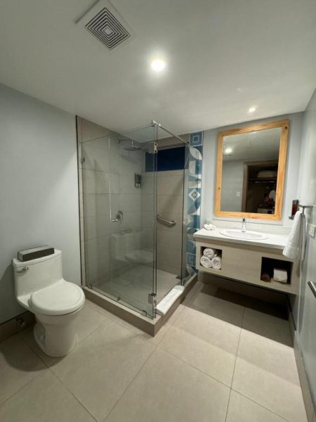 Baño moderno con ducha de cristal, lavabo y espejo en Fiesta Resort All Inclusive Costa Rica