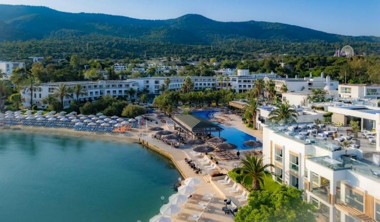 Vista aérea del Samara Hotel Bodrum con piscina exterior, playa privada y montañas al fondo