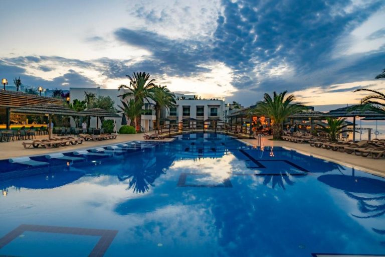Piscina exterior al atardecer con tumbonas y palmeras en Samara Hotel Bodrum Ultra All Inclusive