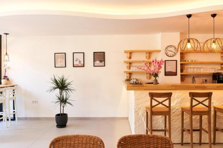 Bar y zona de recepción con encimera de madera y taburetes del hotel Audo Local