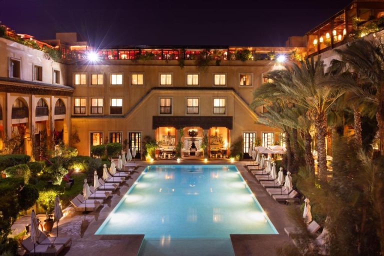 Piscina exterior iluminada de noche con tumbonas en Les Jardins de la Koutoubia, Marrakech
