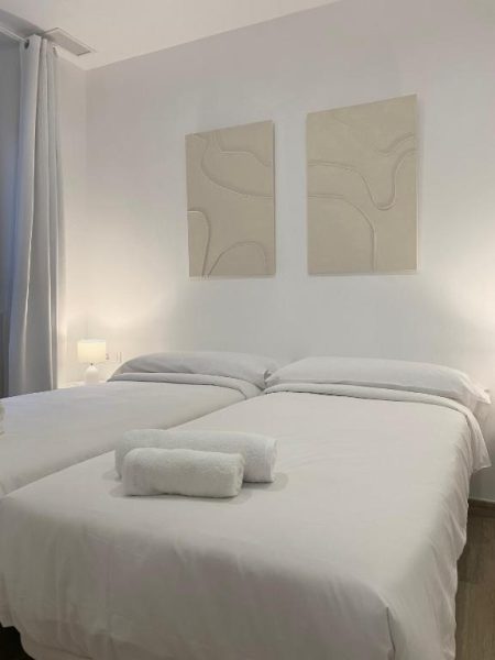 Habitación doble con camas individuales y decoración minimalista en blanco en Vigablanca Apartments