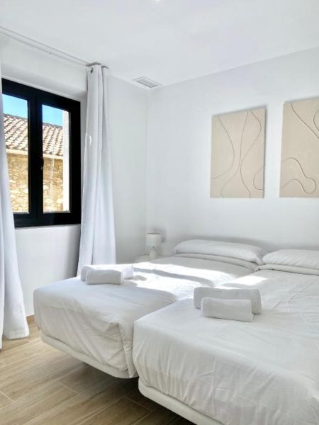 Habitación doble con dos camas individuales y decoración blanca minimalista en Vigablanca Apartments