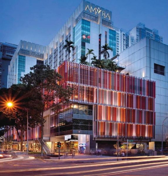 Fachada exterior iluminada del Amara Singapore con diseño moderno y lamas rojas al anochecer