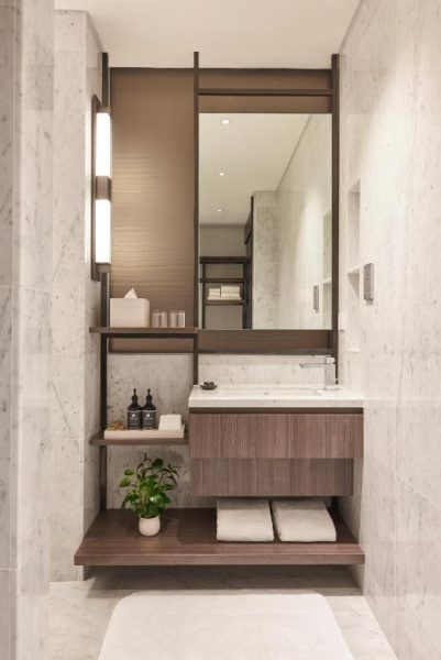 Baño moderno con mármol blanco, lavabo flotante y estanterías de madera en Amara Singapore