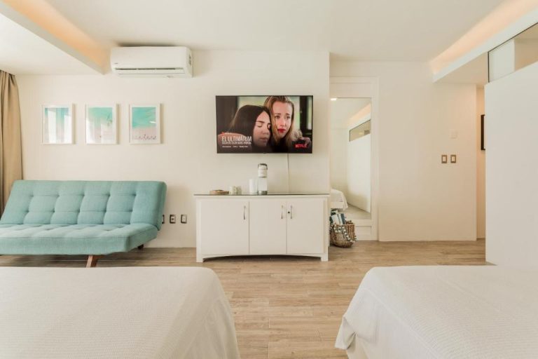 Habitación doble con smart TV Netflix y sofá turquesa en The Ocean Vibes Suites by Casa Paraíso
