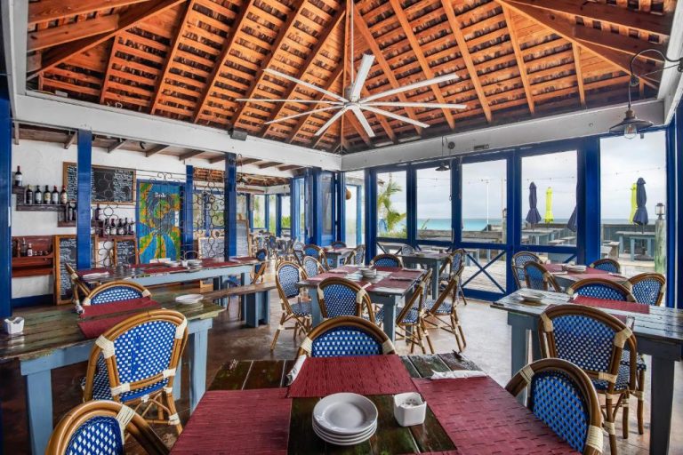 Restaurante interior con techo de madera y vistas al mar turquesa en Pineapple Fields Resort