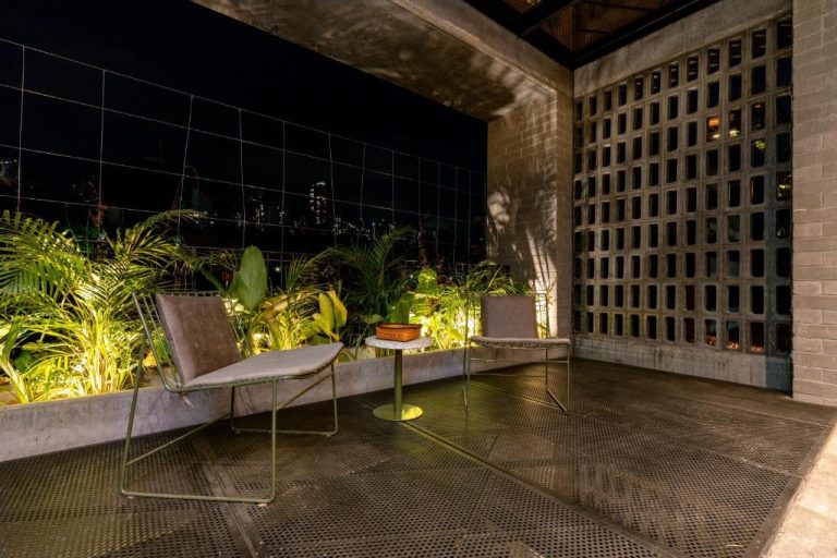 Terraza exterior nocturna con sillones y plantas tropicales en Primavera Luxury Apartments Medellín