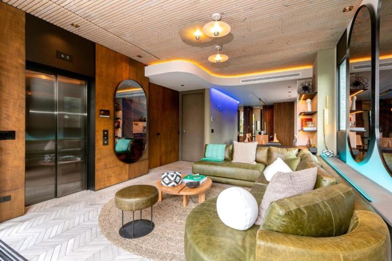 Lujoso salón con sofás de cuero verde y ascensor privado en Primavera Luxury Apartments Medellín