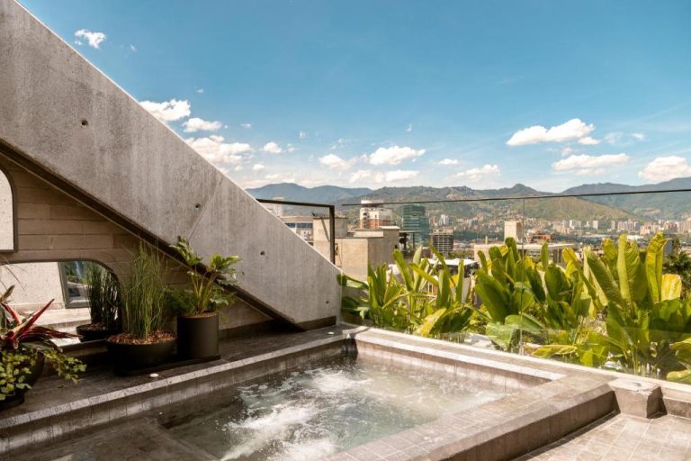 Jacuzzi en terraza con vistas panorámicas de la ciudad y montañas en Primavera Luxury Apartments Medellín