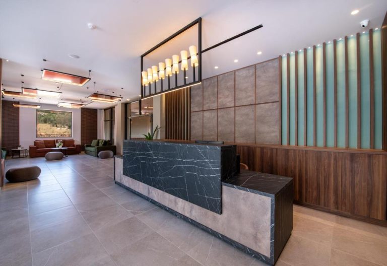 Recepción moderna con mostrador de mármol negro y elegante iluminación en Kiani Beach Resort