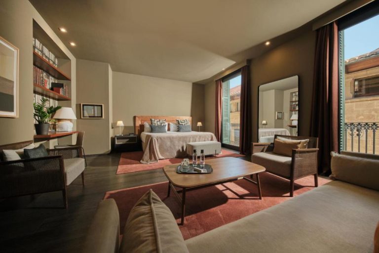 Suite de lujo con salón y cama doble en Can Alomar Hotel, decoración elegante con balcón exterior