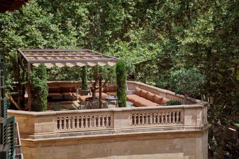 Terraza exterior con sofás y pérgola del Can Alomar Hotel rodeada de vegetación mediterránea