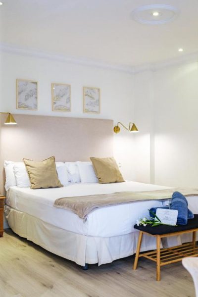 Habitación doble con cama matrimonial y decoración elegante en dorado del Hotel Ciutat Jardi