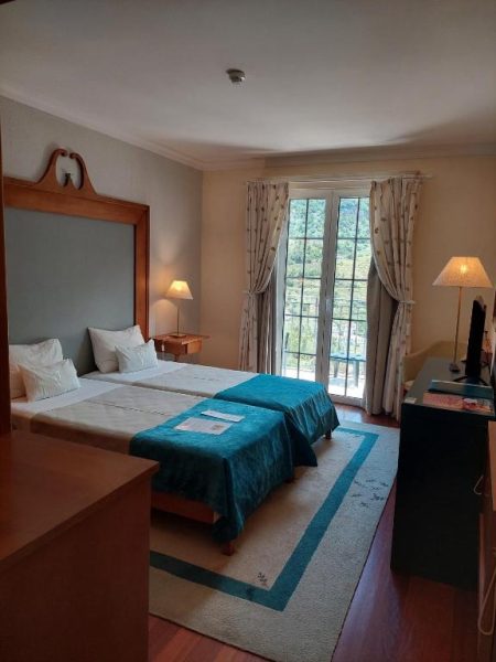 Habitación doble con camas y vistas al jardín desde balcón en Estalagem do Vale