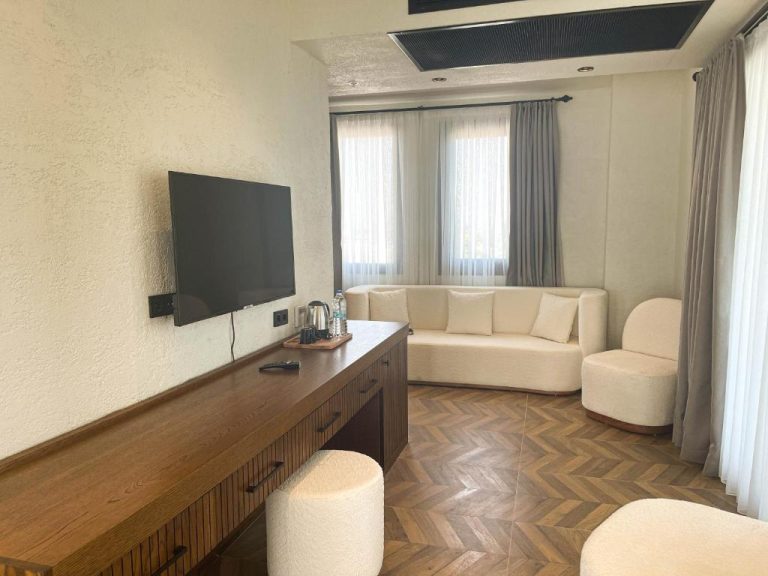 Salón con televisión de pantalla plana y sofá blanco en Now Boutique Hotel