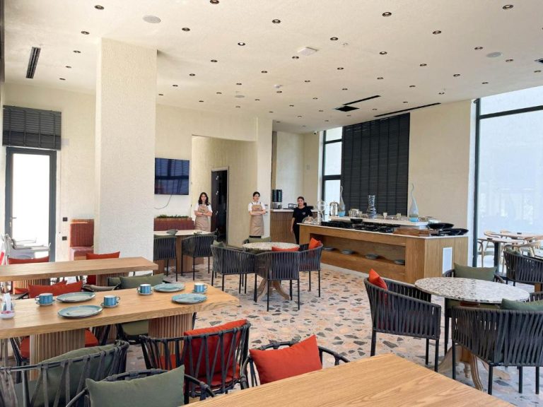 Restaurante moderno con mesas de madera y sillas coloridas en el Now Boutique Hotel, listo para el servicio
