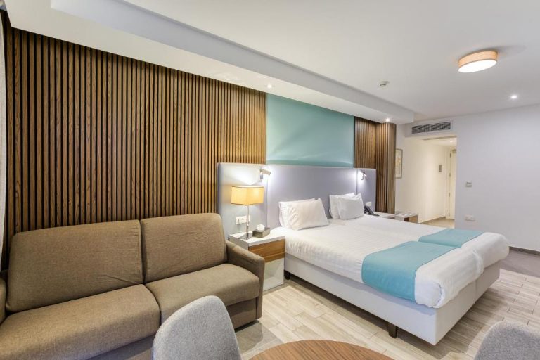 Habitación doble moderna con cama king y sofá en Solana Hotel & Spa, decoración en tonos azules y madera