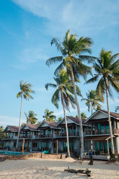 Fachada del Laemsui Beach Hotel con palmeras tropicales, piscina y arena blanca en primera línea de playa
