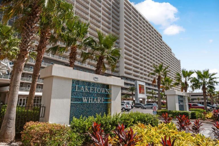 Fachada exterior del complejo Laketown Wharf con palmeras y acceso directo a la playa en Panama City Beach