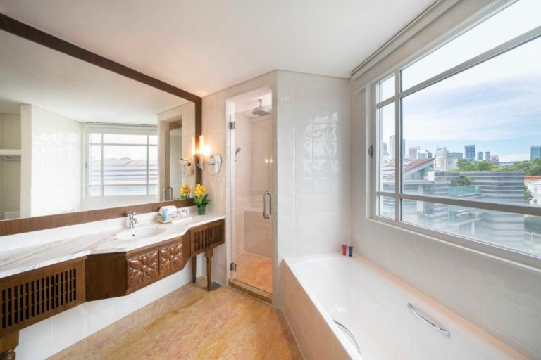 Lujoso baño con bañera y ducha independiente con vistas a la ciudad en Rendezvous Hotel Singapore