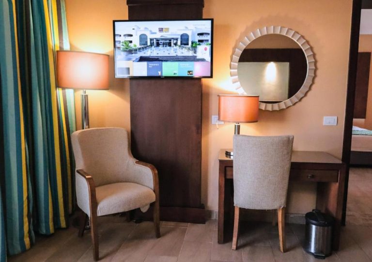 Habitación con escritorio, sillón, televisor y espejo decorativo en el hotel Fun & Sun Naama Waves