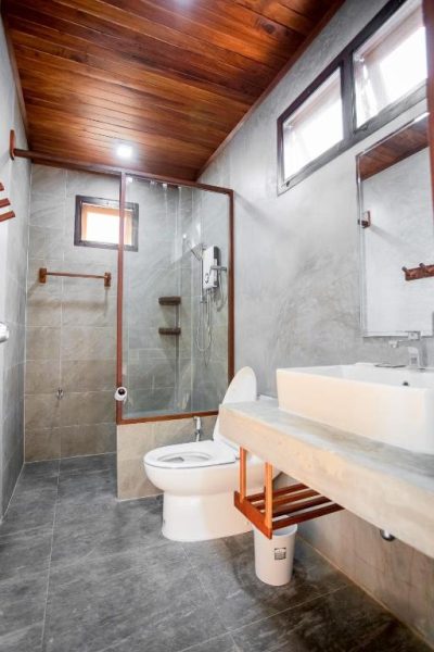 Baño moderno con ducha de cristal, lavabo y techo de madera en Laemsui Beach Hotel