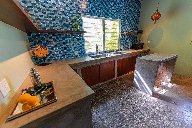 Cocina moderna con encimeras de cemento y azulejos azules en Casa de Amistad Guesthouse