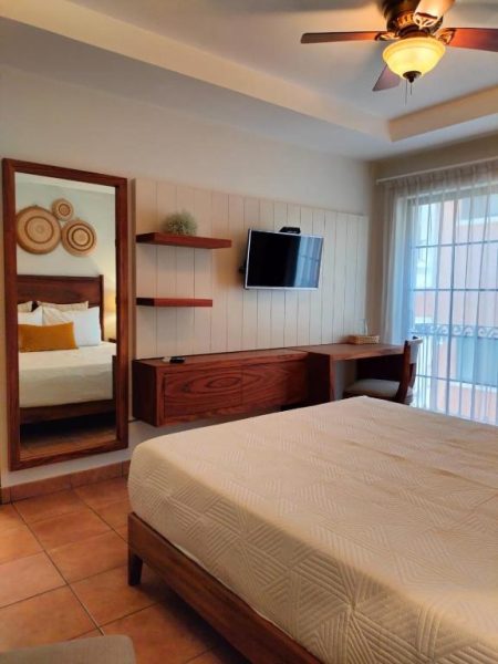 Habitación doble con cama matrimonial, televisión y espejo de pie en Hotel Colli