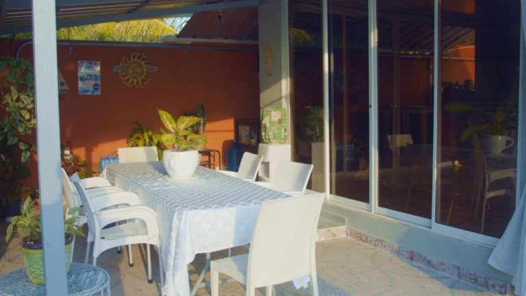 Terraza comedor exterior con mesa y sillas blancas rodeada de plantas en Hotel Vista al Morro
