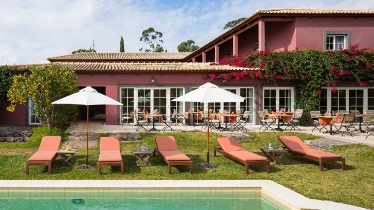 Piscina exterior con tumbonas y terraza del Hotel Atrio rodeada de jardines y flores