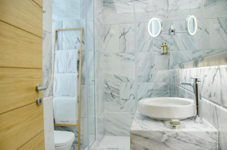 Baño de mármol blanco con ducha y lavabo del Browns Central Hotel en Portugal
