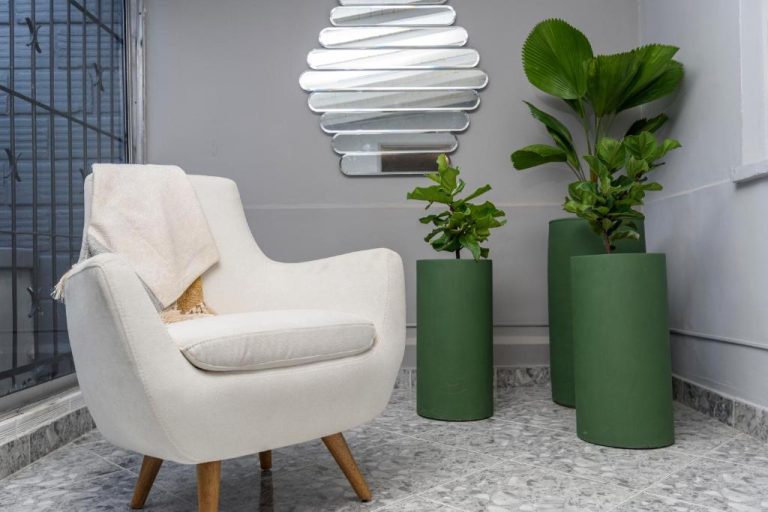 Sillón blanco con plantas decorativas en cilindros verdes en el lobby del Hotel Hola Medellín