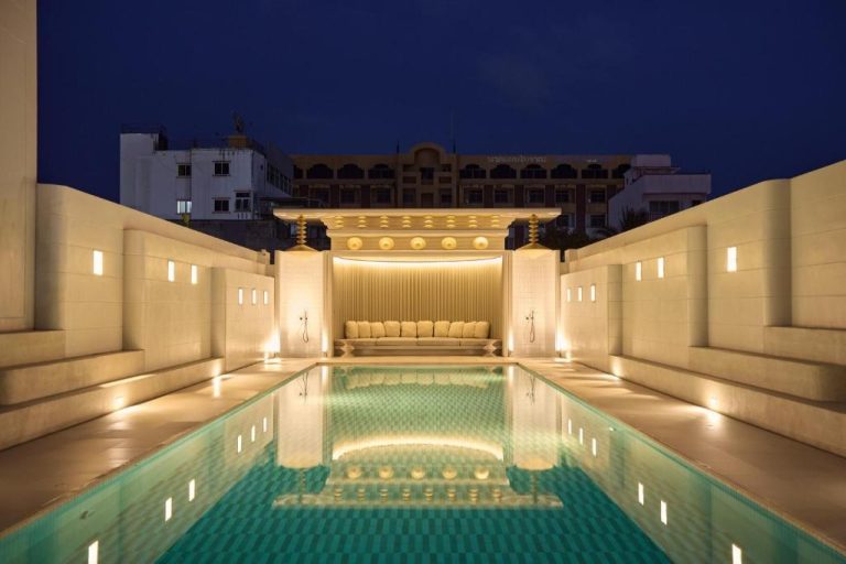 Piscina exterior iluminada de noche con zona lounge elegante en el hotel Arco Phuket Town