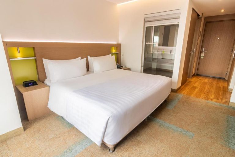 Habitación con cama king size y baño acristalado en Biohotel Organic Suites Bogotá Usaquén