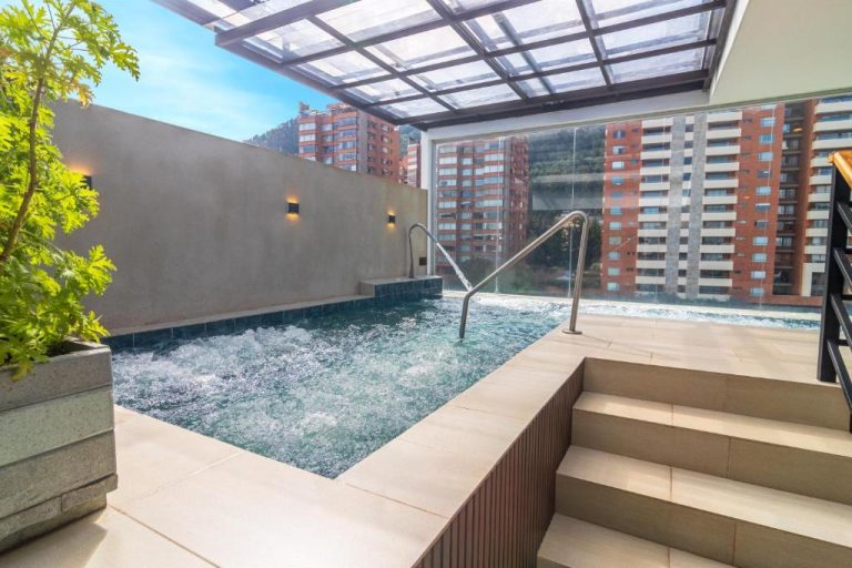 Jacuzzi exterior con techo de cristal y vistas a edificios en Biohotel Organic Suites Bogotá Usaquén