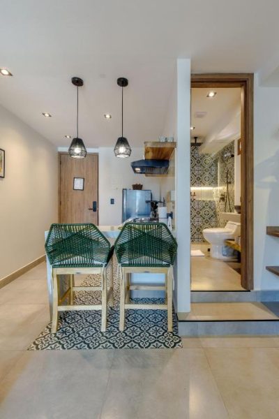 Cocina americana con taburetes verdes y baño con azulejos en De la Cruz Studio Apartments