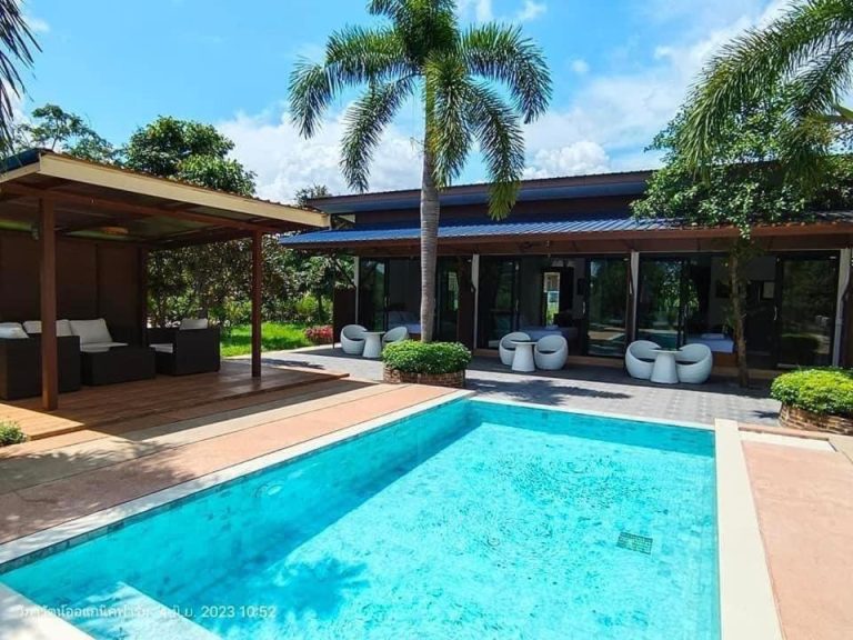 Piscina exterior con terraza y zona lounge del Coco Residence en Si Saket, Tailandia