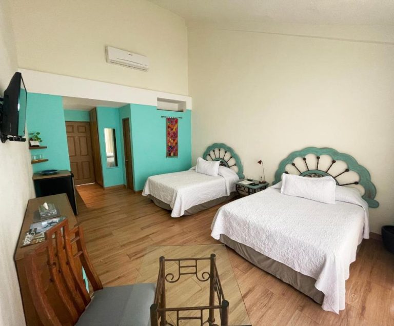Habitación doble con cabeceros artesanales turquesa y paredes coloridas en Marisol Hotel Boutique